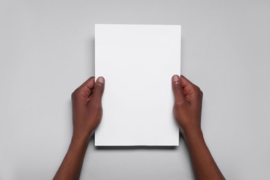 Photo of African American man holding sheet of paper on white background, closeup. Mockup for design