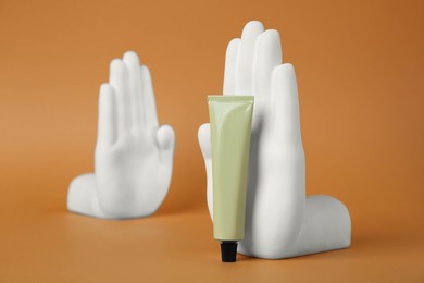 Composition with tube of hand cream on orange background, space for text