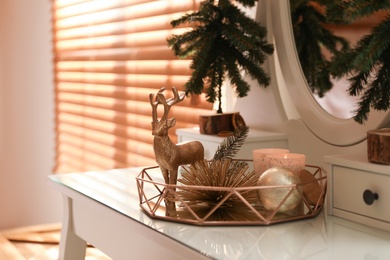 Composition with decorative reindeer and Christmas tree on dressing table near window