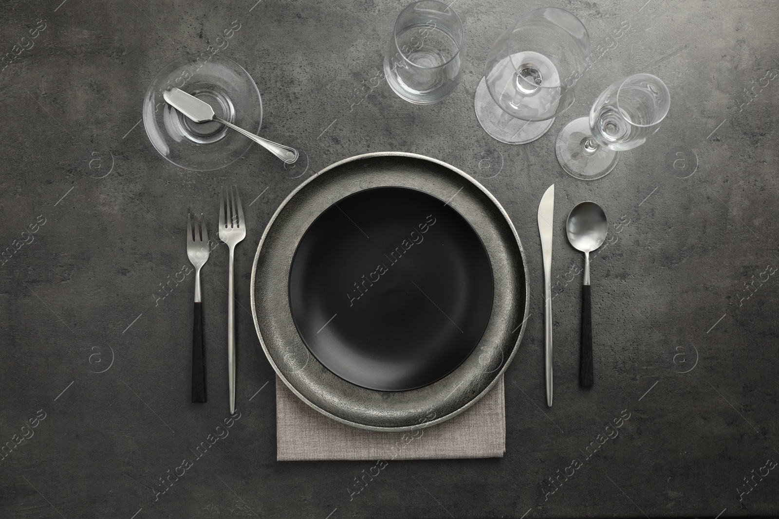 Photo of Stylish setting with cutlery, glasses and plates on black table, flat lay