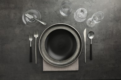 Stylish setting with cutlery, glasses and plates on black table, flat lay