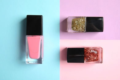 Photo of Bottles of nail polish on color background, top view