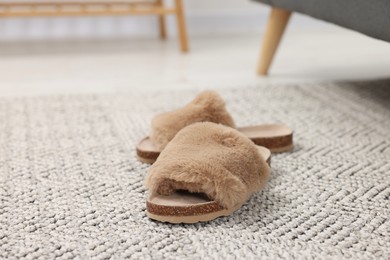 Photo of Brown soft slippers on crochet carpet indoors, closeup