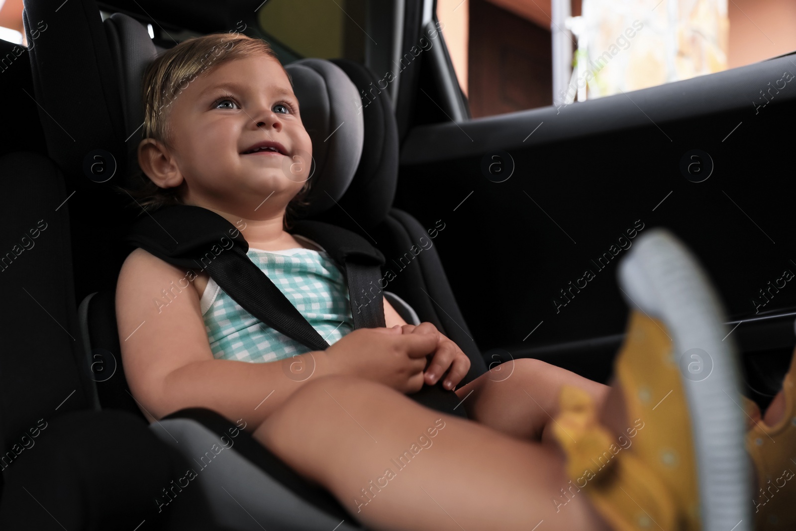 Photo of Cute little girl sitting in child safety seat inside car