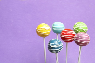 Photo of Many bright delicious cake pops on color background. Space for text