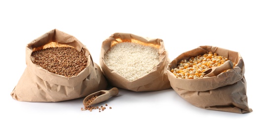 Paper bags with different types of grains and cereals on white background