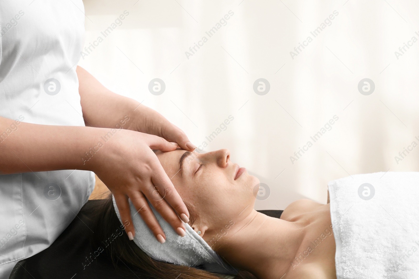 Photo of Cosmetologist making face massage to client in clinic, closeup