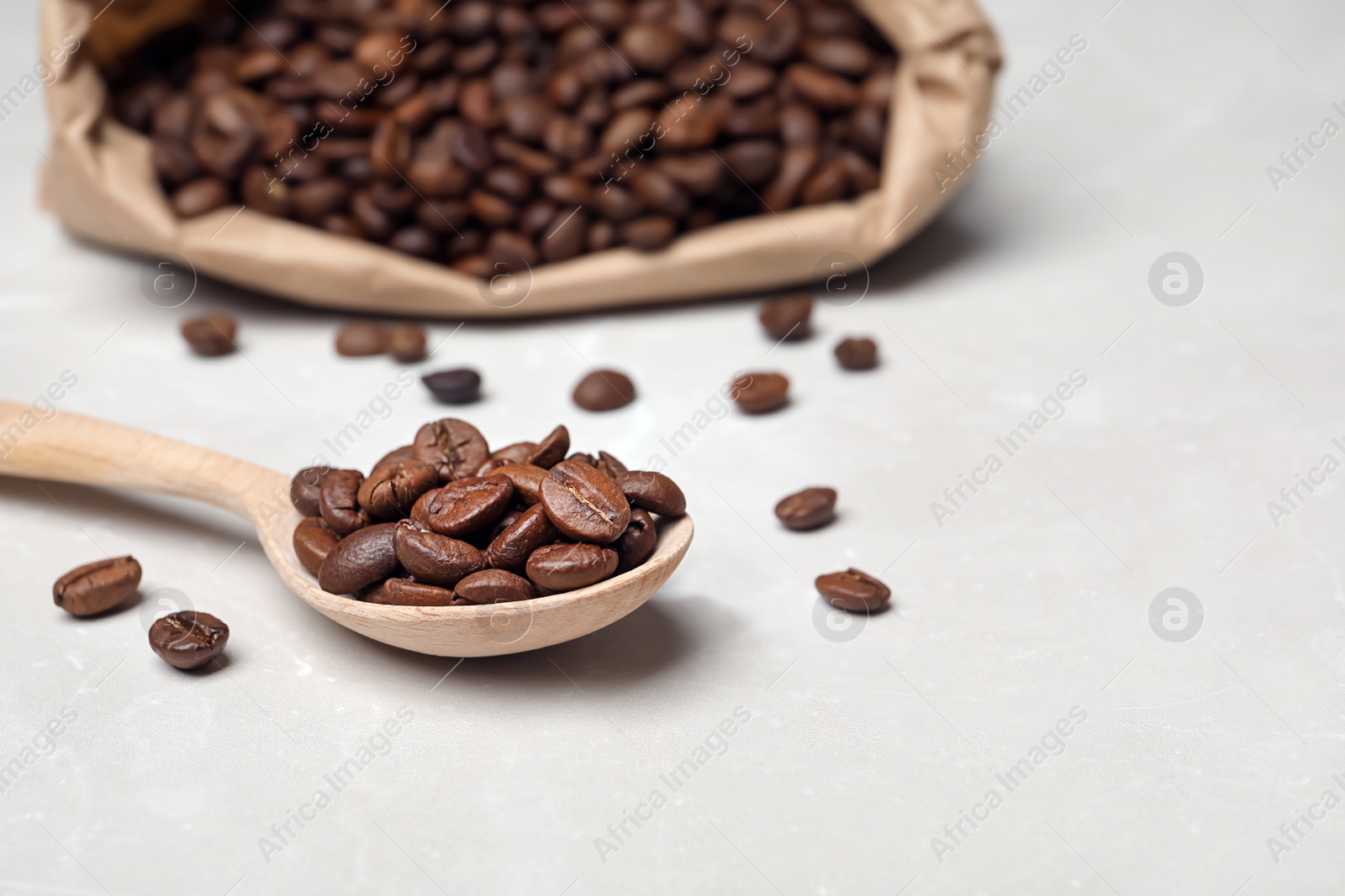 Photo of Spoon with coffee beans on light background