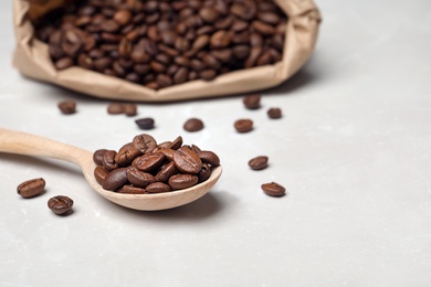 Spoon with coffee beans on light background