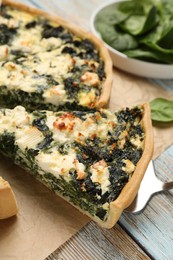 Taking piece of delicious homemade spinach quiche on table, closeup