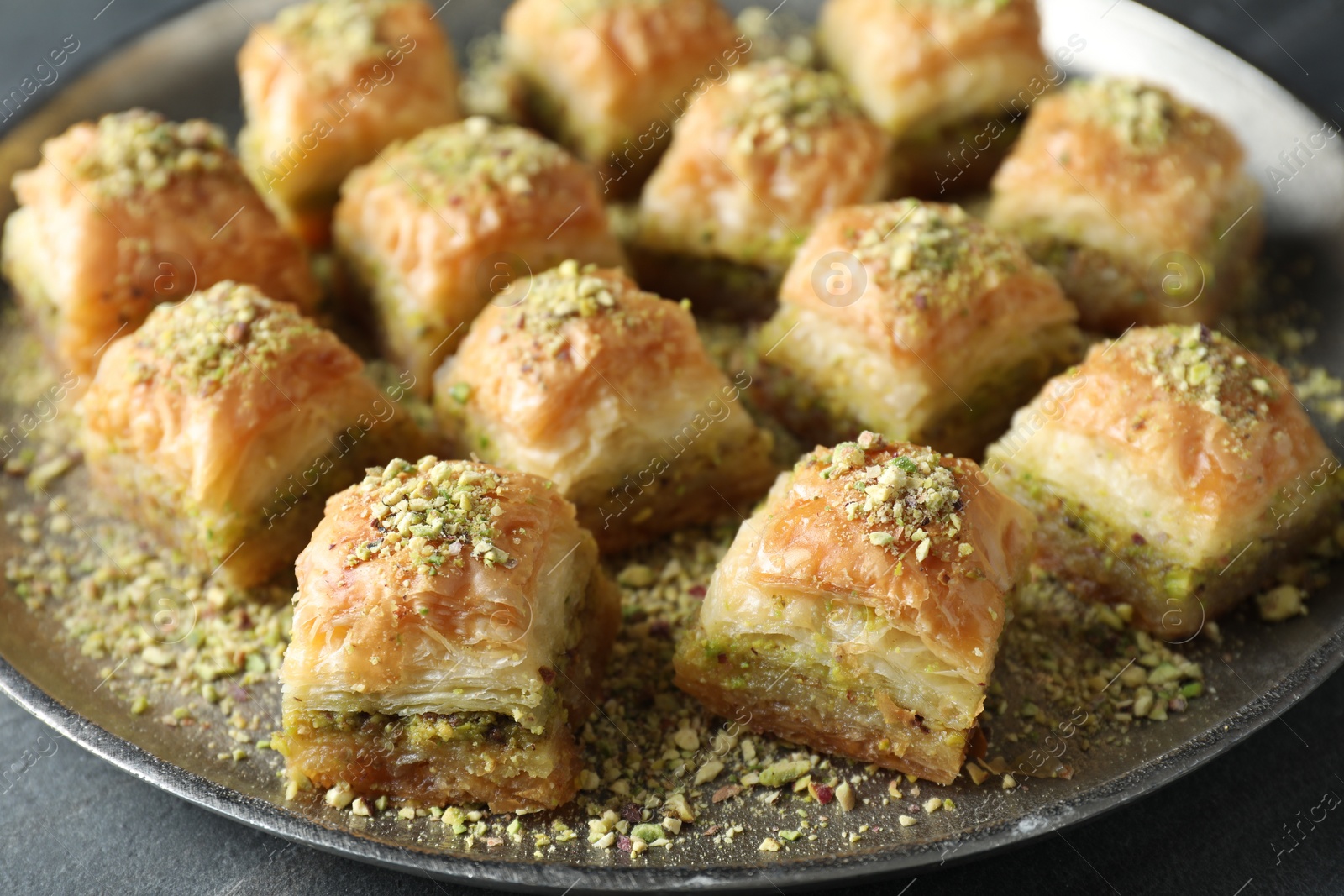 Photo of Delicious fresh baklava with chopped nuts on grey table, closeup. Eastern sweets