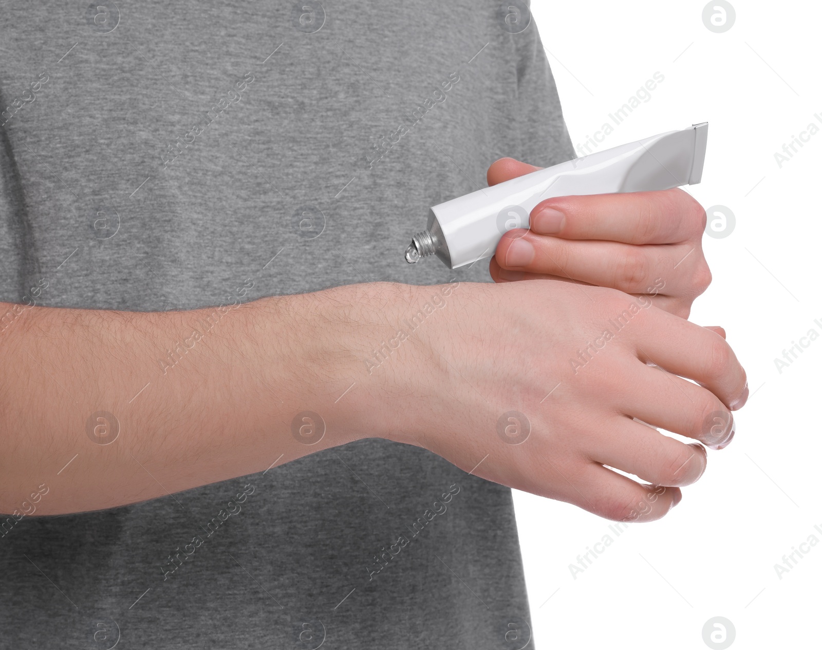 Photo of Man applying ointment from tube onto his hand on white background, closeup