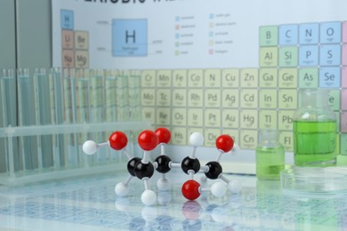 Photo of Molecular model and laboratory glassware against periodic table