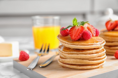 Photo of Tasty pancakes with berries on wooden board