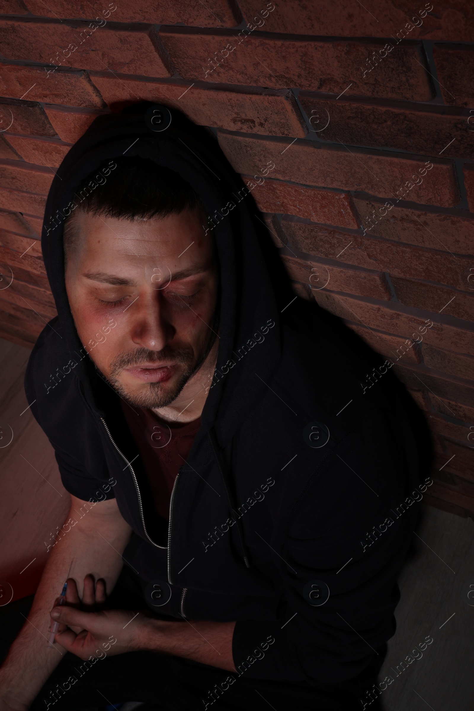 Photo of Overdosed drug addicted man near brick wall