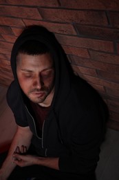 Photo of Overdosed drug addicted man near brick wall