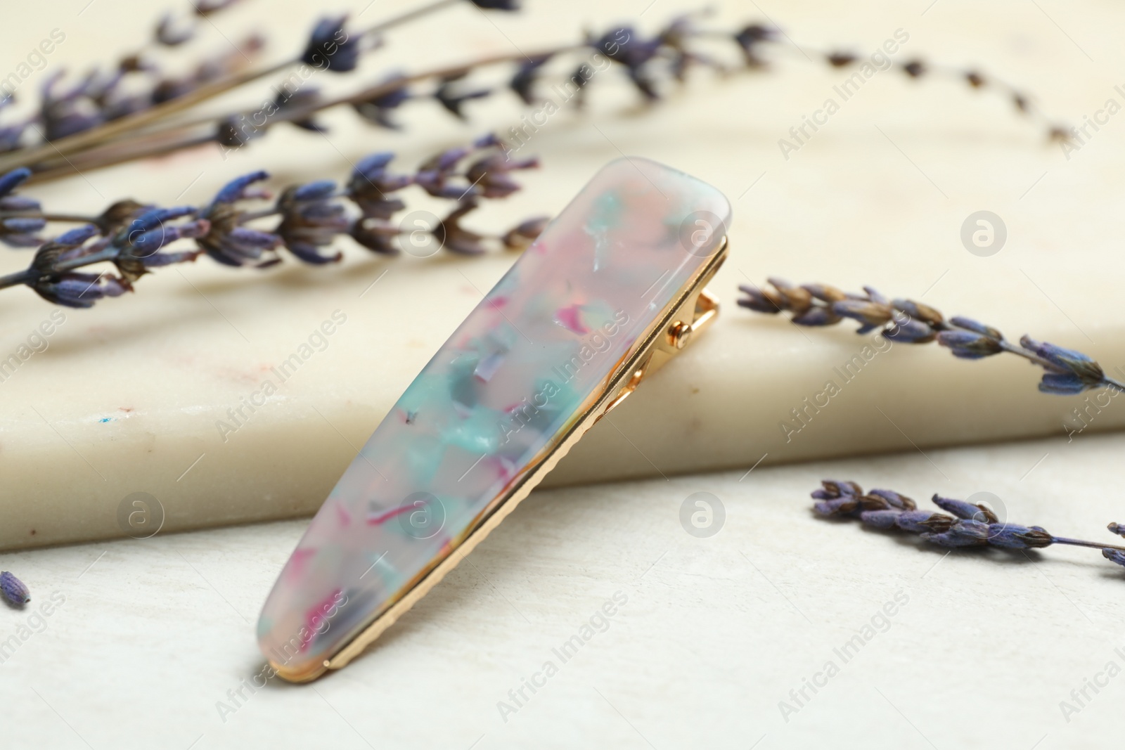 Photo of Beautiful hair clip and flowers on white table, closeup