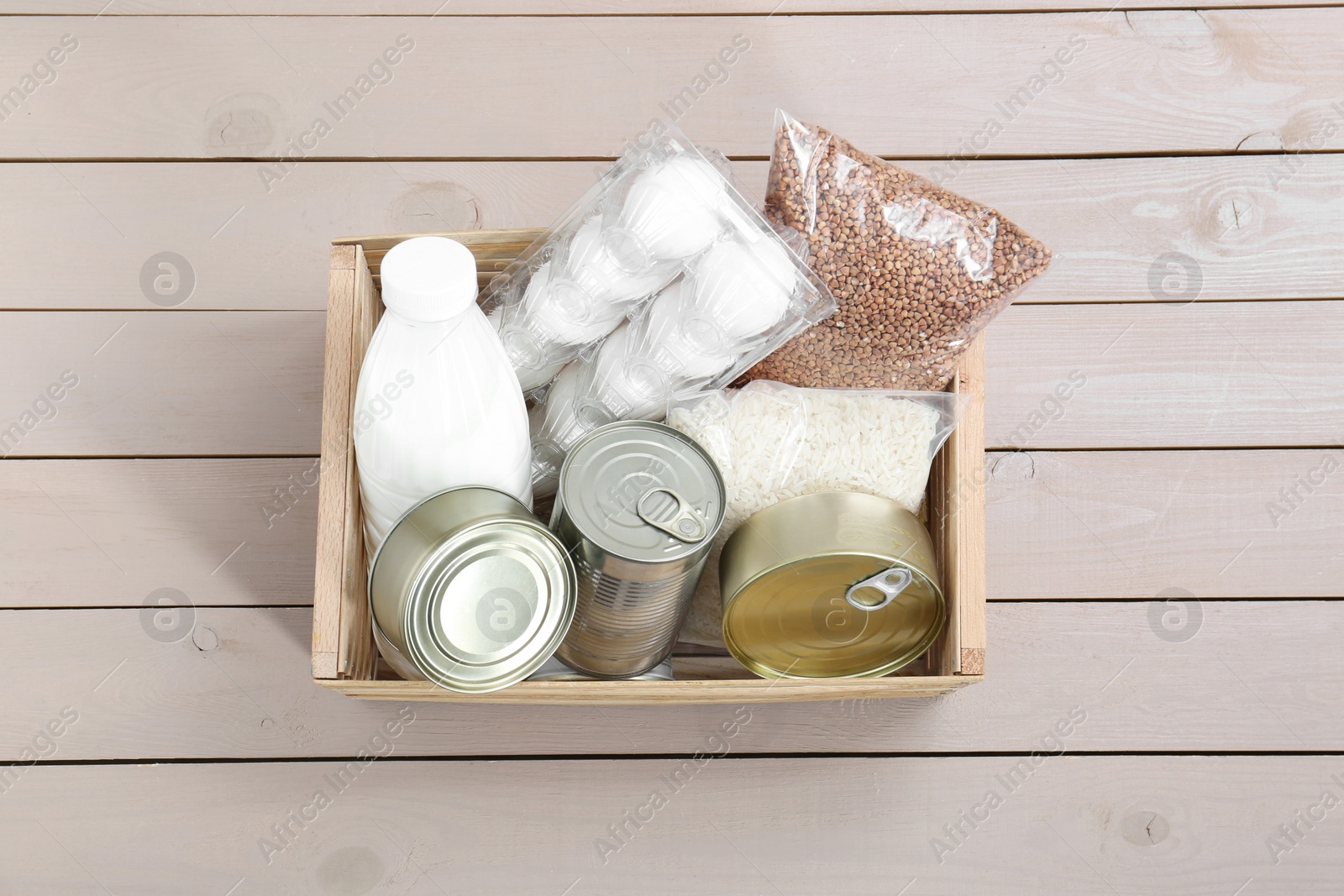 Photo of Donation box with food products on wooden table, top view