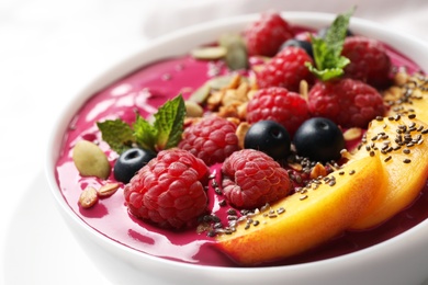 Delicious acai smoothie with granola and berries in dessert bowl on table, closeup