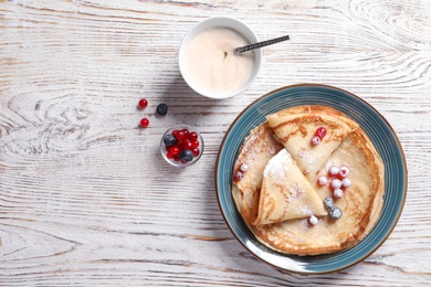 Photo of Flat lay composition with thin pancakes on wooden background