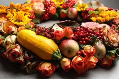 Photo of Beautiful autumnal wreath with flowers, berries and fruits on light grey background, closeup
