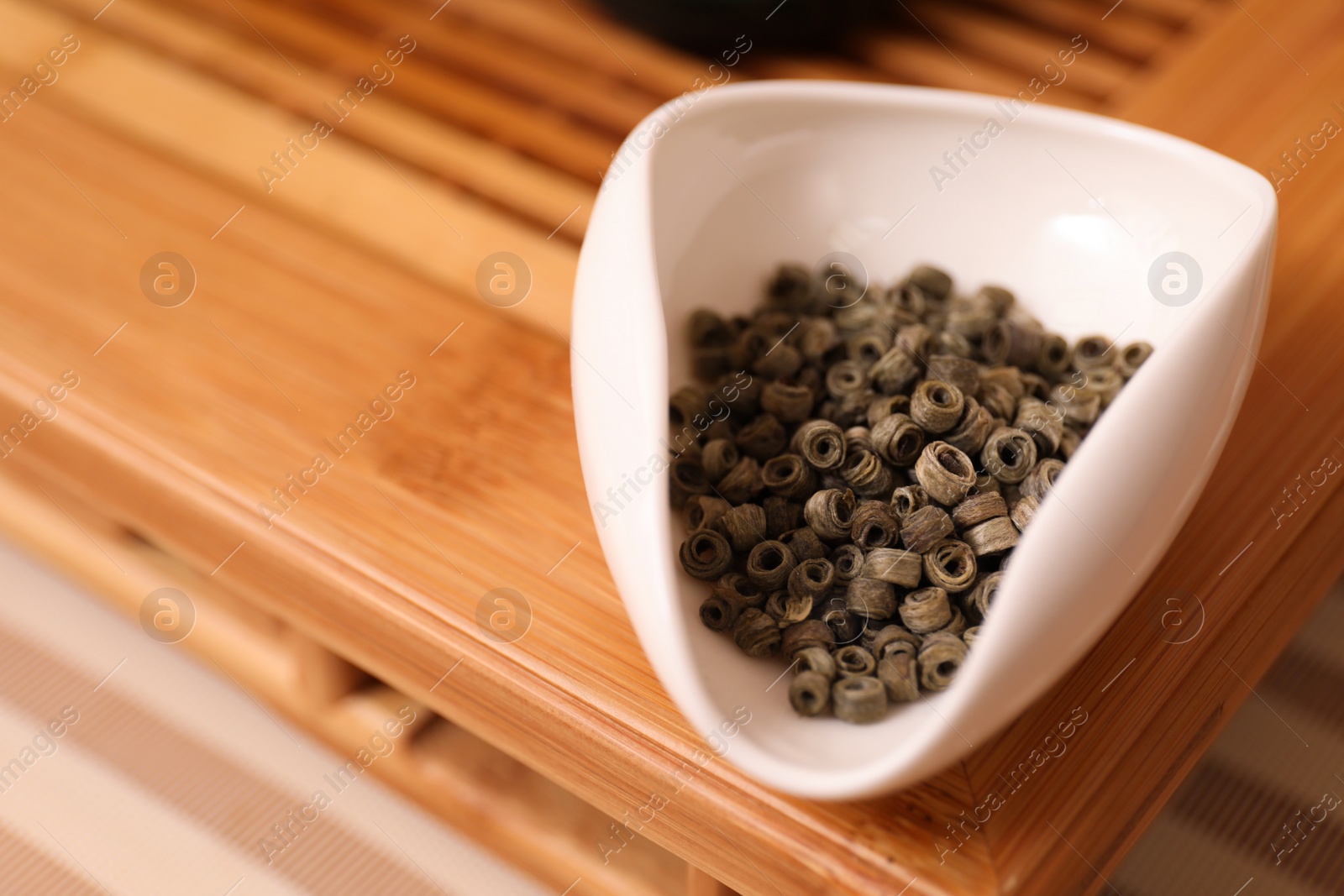 Photo of Beautiful bowl with dry green tea on wooden table, space for text. Traditional ceremony