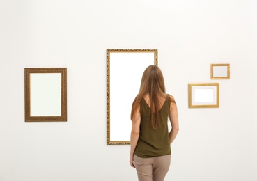 Photo of Young woman viewing exposition in modern art gallery