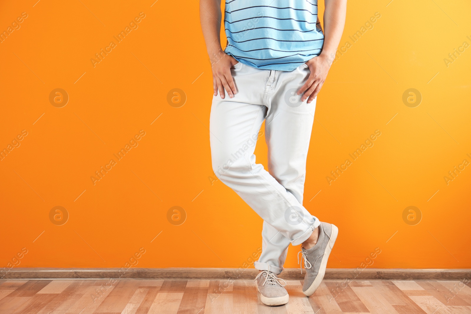 Photo of Young man in stylish jeans near color wall