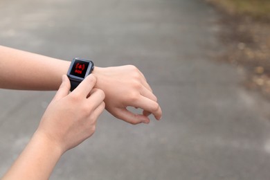 Image of Woman using SOS function on smartwatch outdoors, closeup