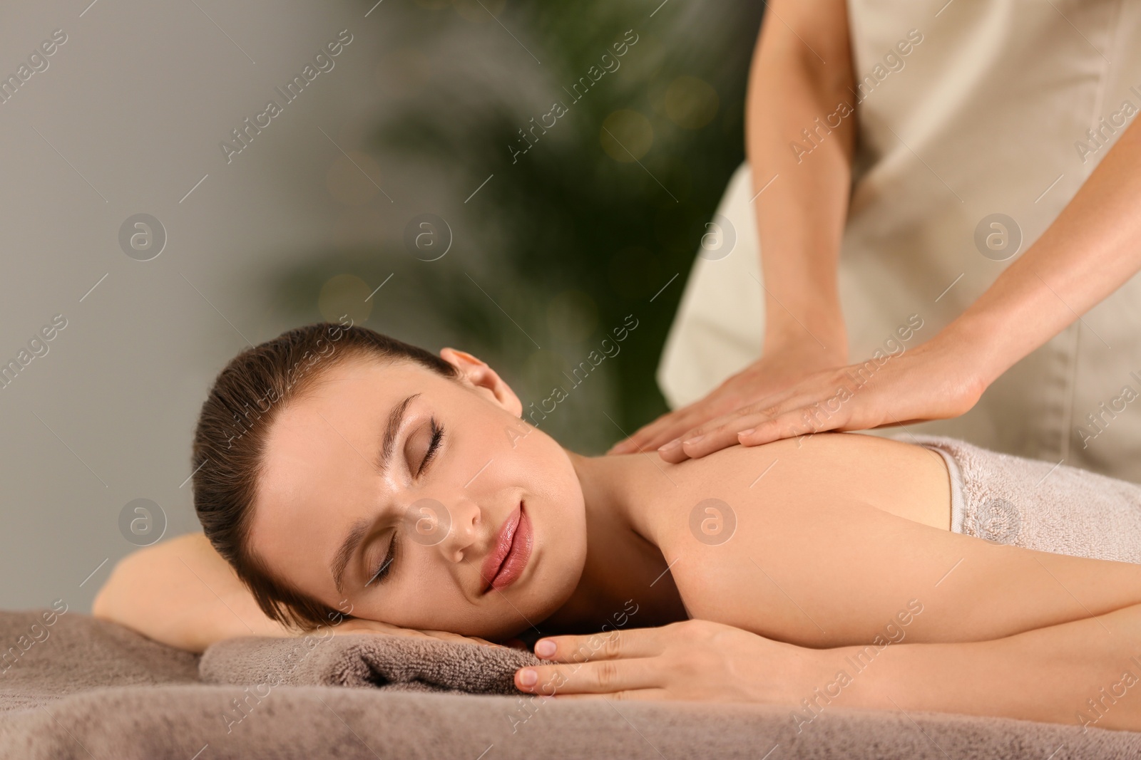 Photo of Beautiful young woman enjoying massage in spa salon