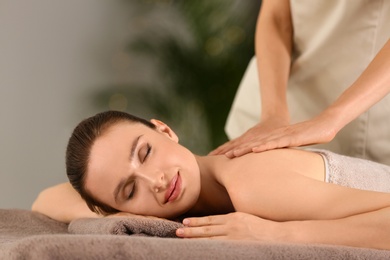 Beautiful young woman enjoying massage in spa salon