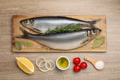 Photo of Delicious salted herrings and ingredients on wooden table, flat lay