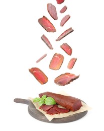 Image of Slices of delicious dry-cured basturma falling onto wooden board against white background