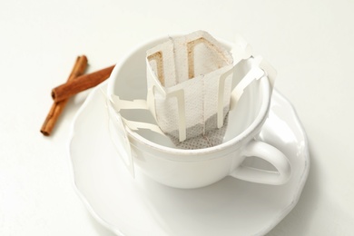 Photo of Drip coffee bag in cup on white table, closeup