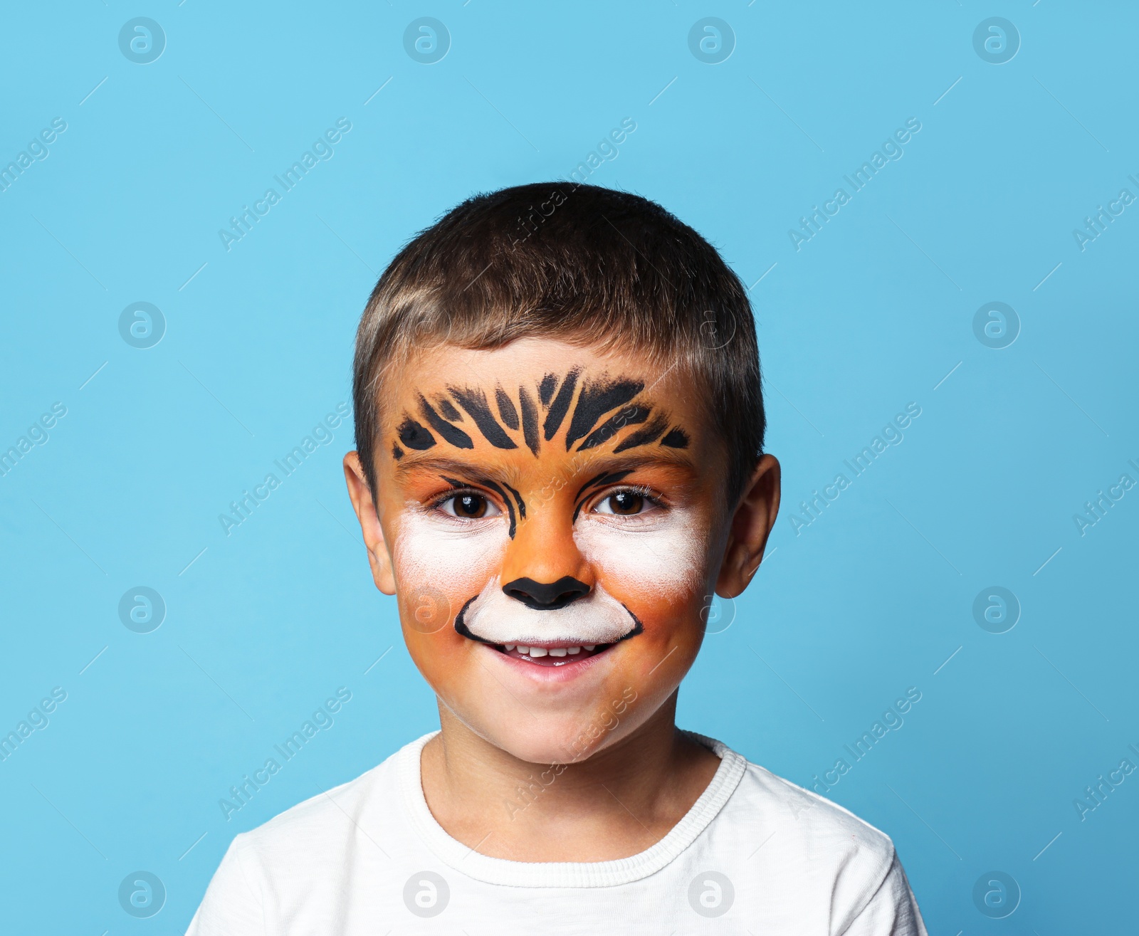 Photo of Cute little boy with face painting on blue background