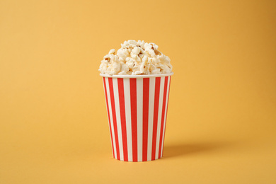 Photo of Delicious popcorn in paper cup on yellow background