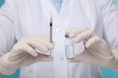 Doctor holding syringe and glass vial, closeup view