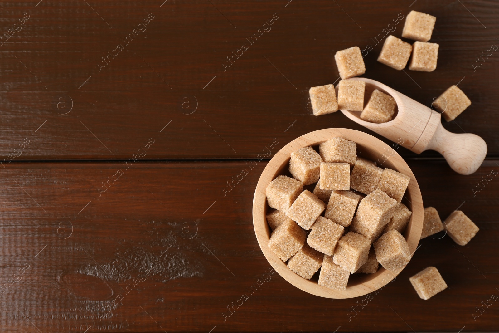 Photo of Brown sugar cubes on wooden table, flat lay. Space for text