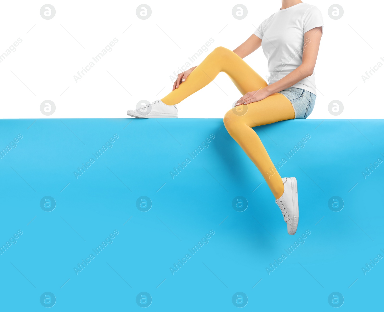 Photo of Woman wearing yellow tights and stylish shoes sitting on color background, closeup. Space for text