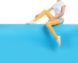 Woman wearing yellow tights and stylish shoes sitting on color background, closeup. Space for text