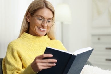 Photo of Happy woman in stylish glasses reading book indoors. Space for text