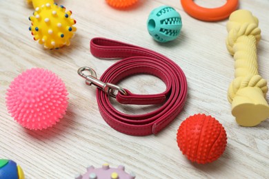 Photo of Red leather dog leash and toys on white wooden background