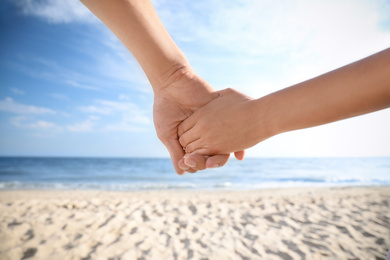 Photo of Couple holding hands on beach, closeup view