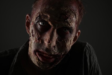 Photo of Scary zombie on dark background, closeup. Halloween monster