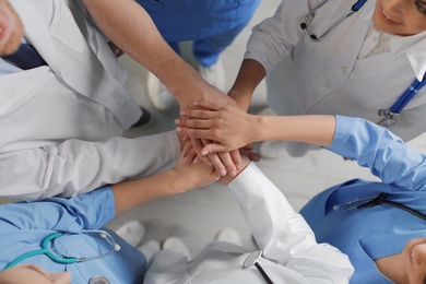 Photo of Young medical doctors putting hands together indoors, top view. Unity concept
