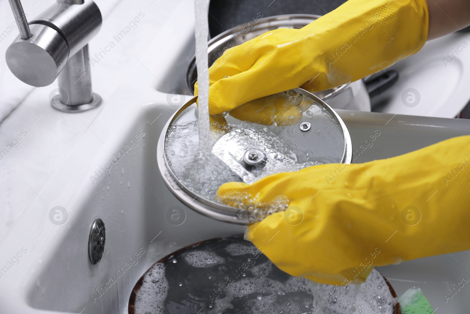 Photo of Woman washing dirty dishes in kitchen sink, closeup