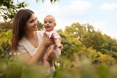 Photo of Happy mother with adorable baby walking in park on sunny day, space for text