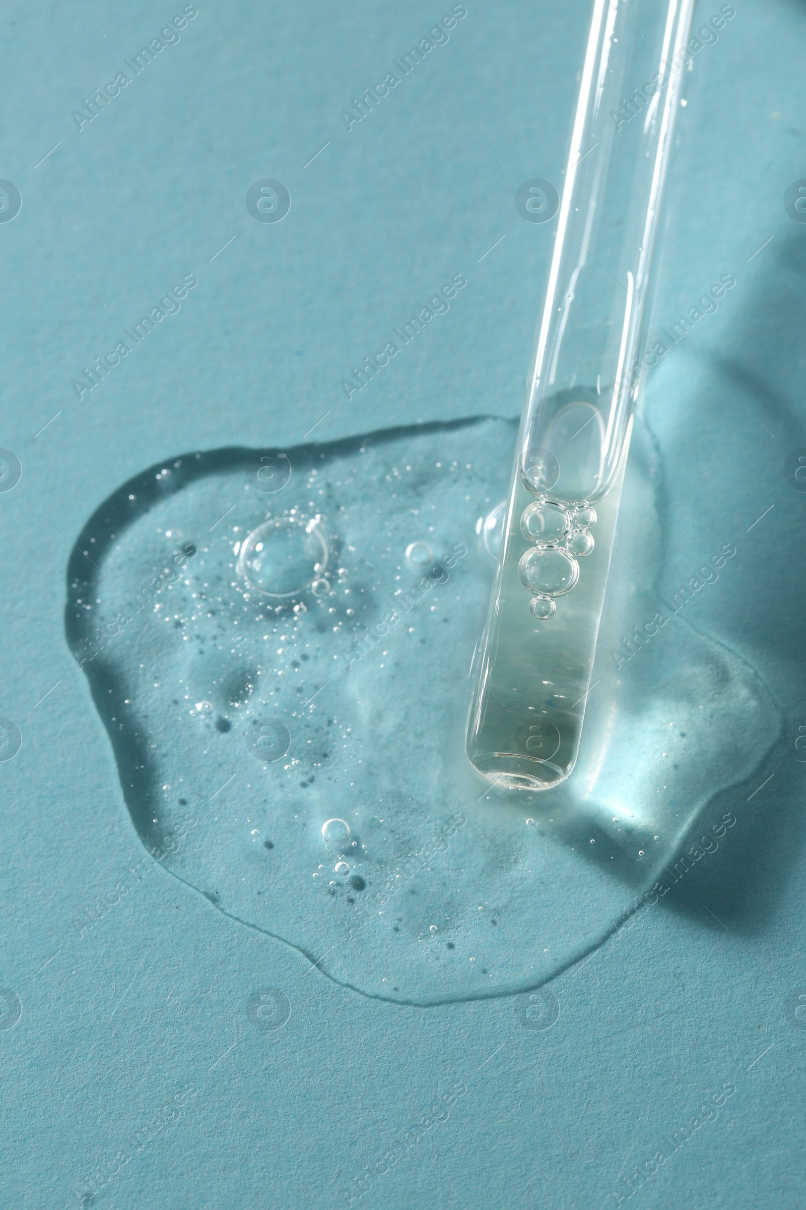 Photo of Pipette with cosmetic serum on light blue background, above view