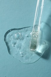 Photo of Pipette with cosmetic serum on light blue background, above view