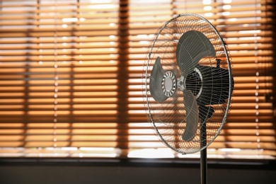 Photo of Modern electric fan near window indoors. Space for text